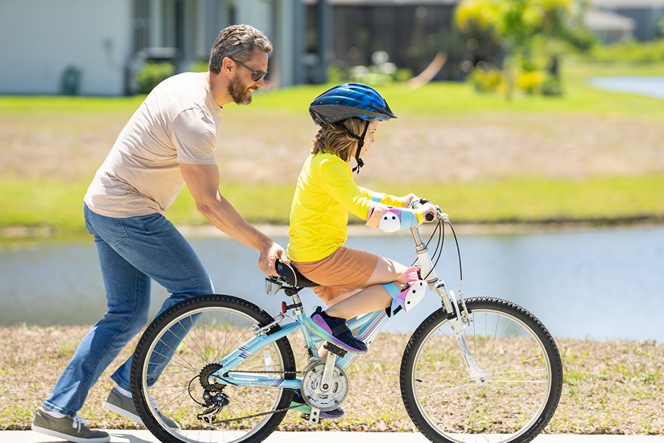 A father teaching a girl to ride a bike outdoors.